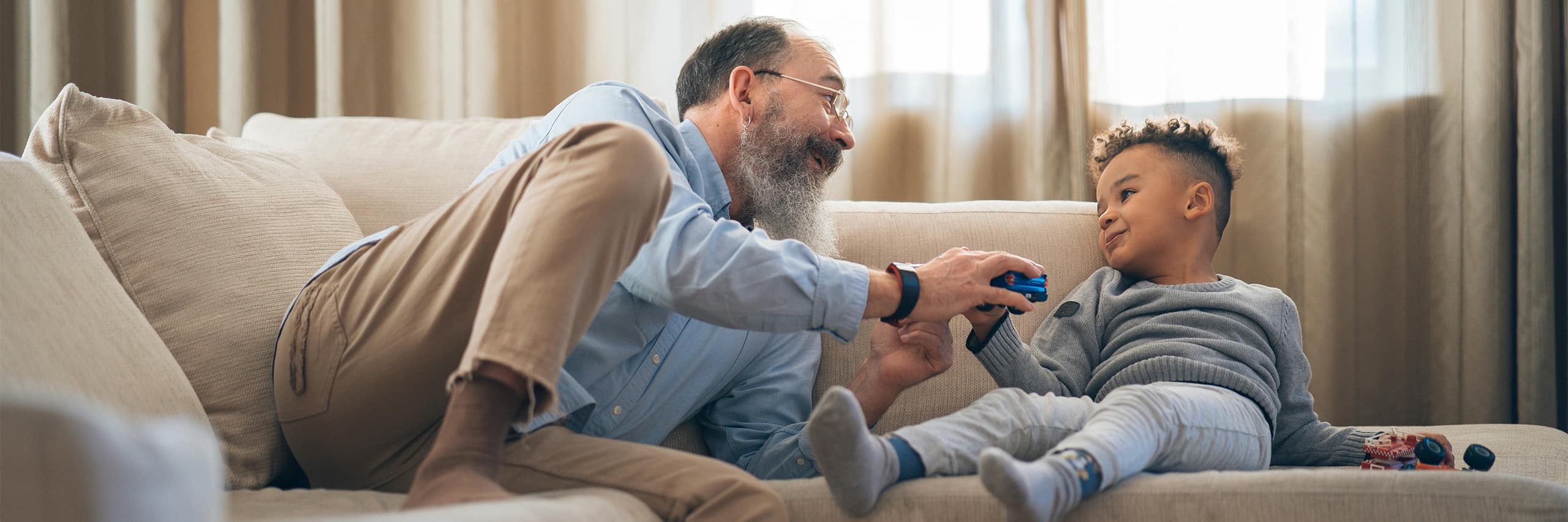Ein älterer Mann und ein Junge spielen auf einem Sofa