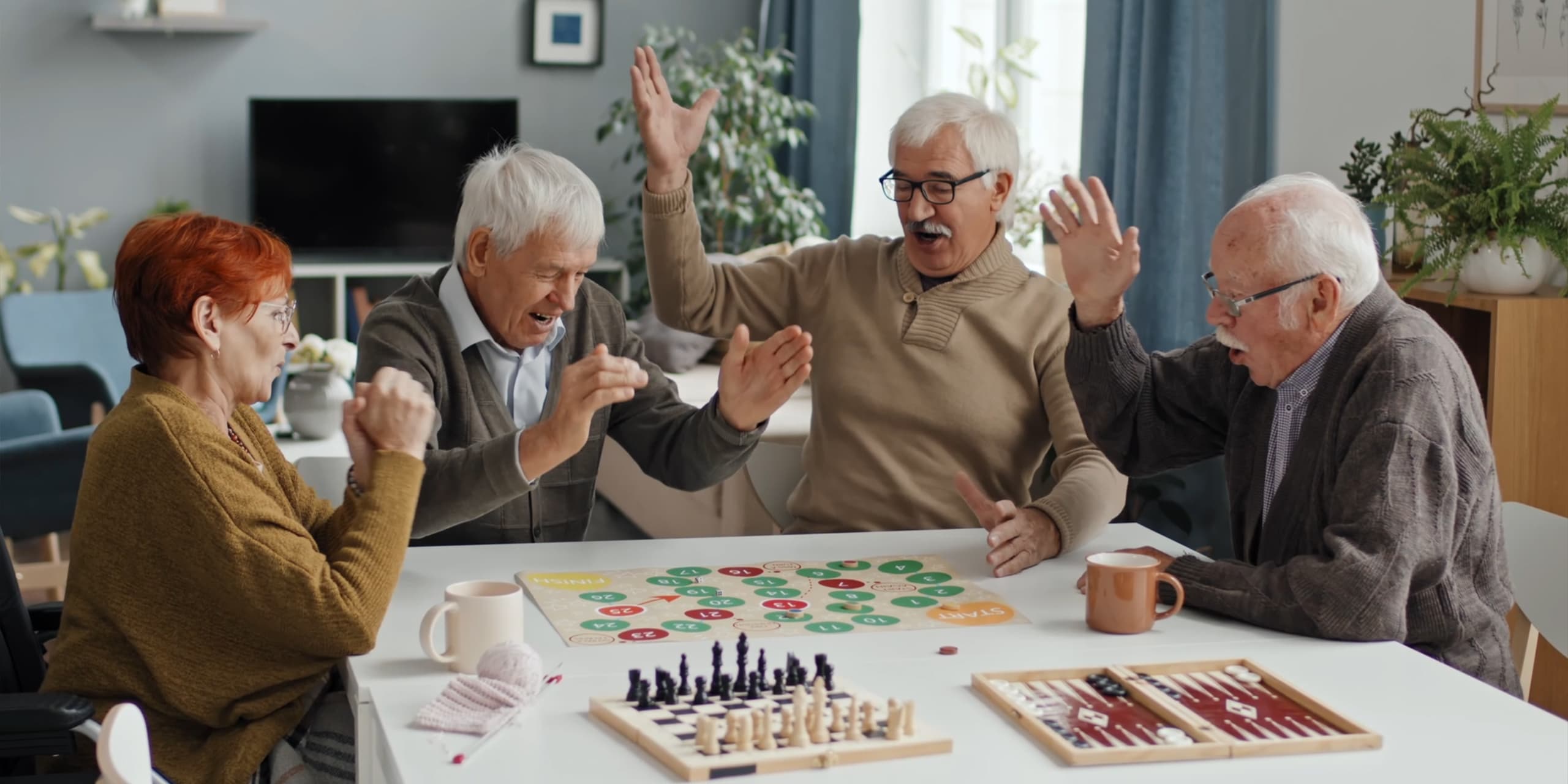 Eine Gruppe von älteren Leuten sitzt am Tisch und spielt ein Brettspiel