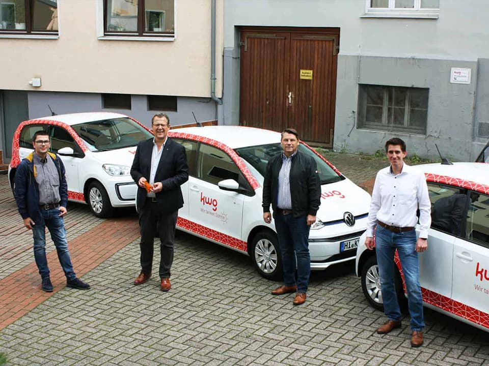 4 männliche Mitarbeitende der kwg stehen vor VW eUP-Autos