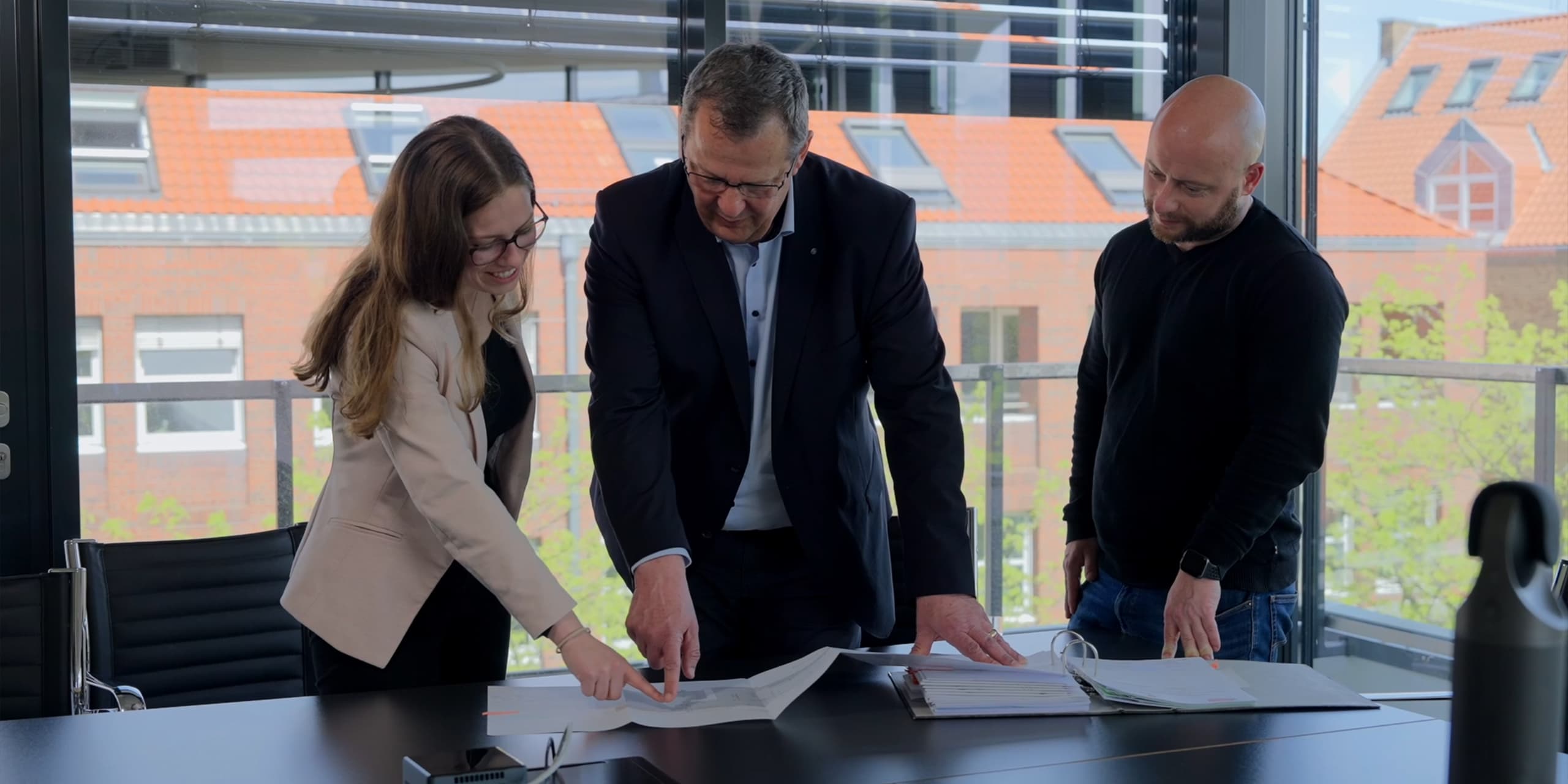 3 Mitarbeitende der kwg stehen an einem Konferenztisch